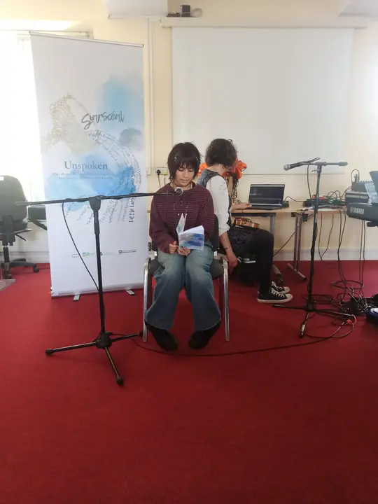 A young writer reading seated at the microphone