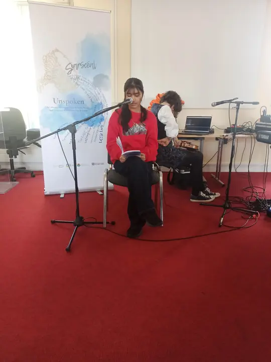 A young writer reading seated at the microphone