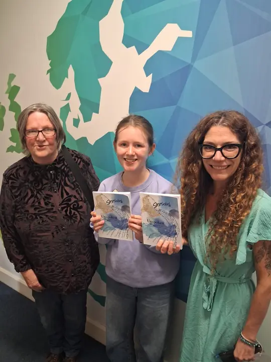 Three people holding copies of Unspoken