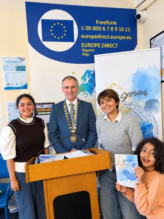 Four people around the lectern, one holding a copy of Unspoken