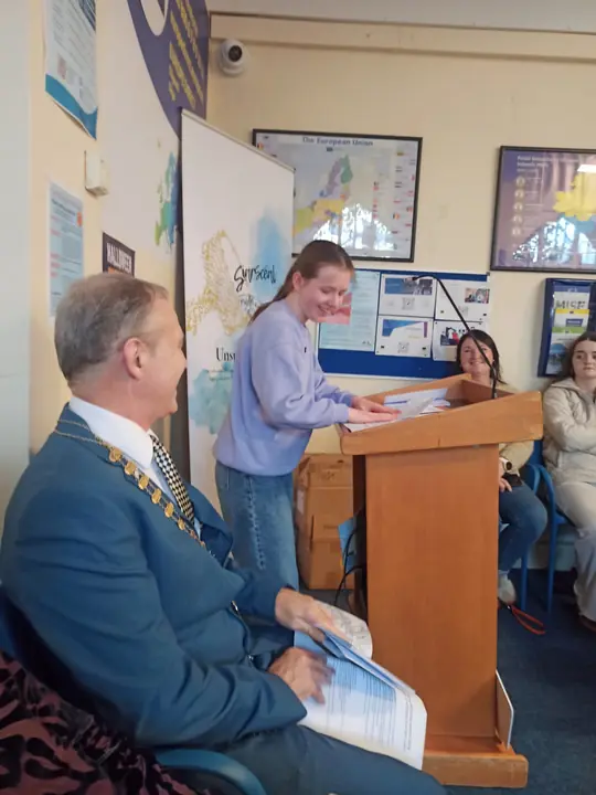 A young writer reading at the lectern, smiling