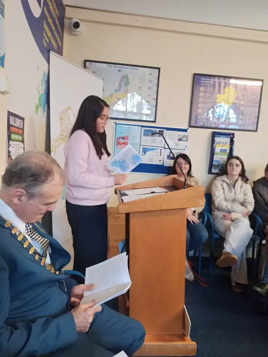 A young writer reading from a printed page at the lectern